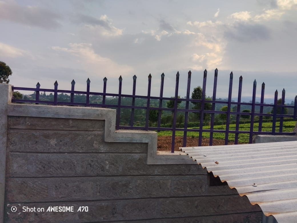 Purple metal fencing spikes on stepped decorative perimeter wall with scenic view