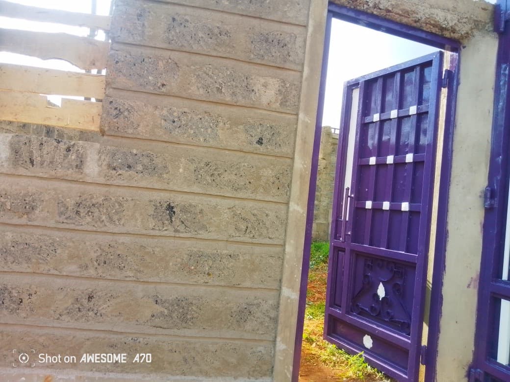 Purple security gate with decorative scrollwork installed in stone wall opening