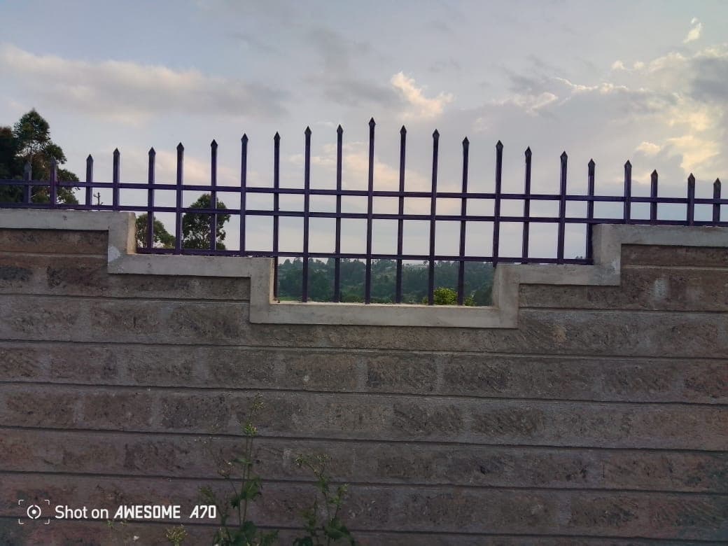 Close-up of perimeter wall with decorative stepped window opening and purple fencing