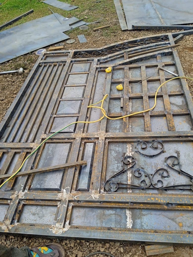 Metal gate frame being fabricated with decorative scrollwork elements