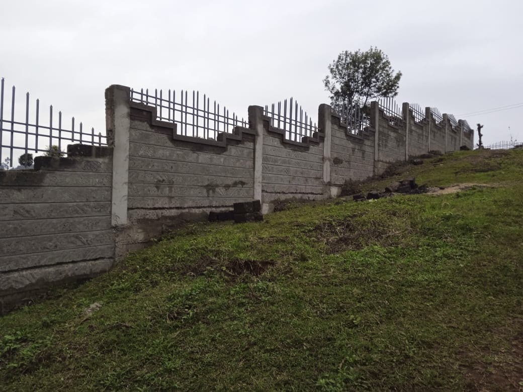 Long stretch of finished wall with decorative stepped tops and metal railings climbing up grassy hillside