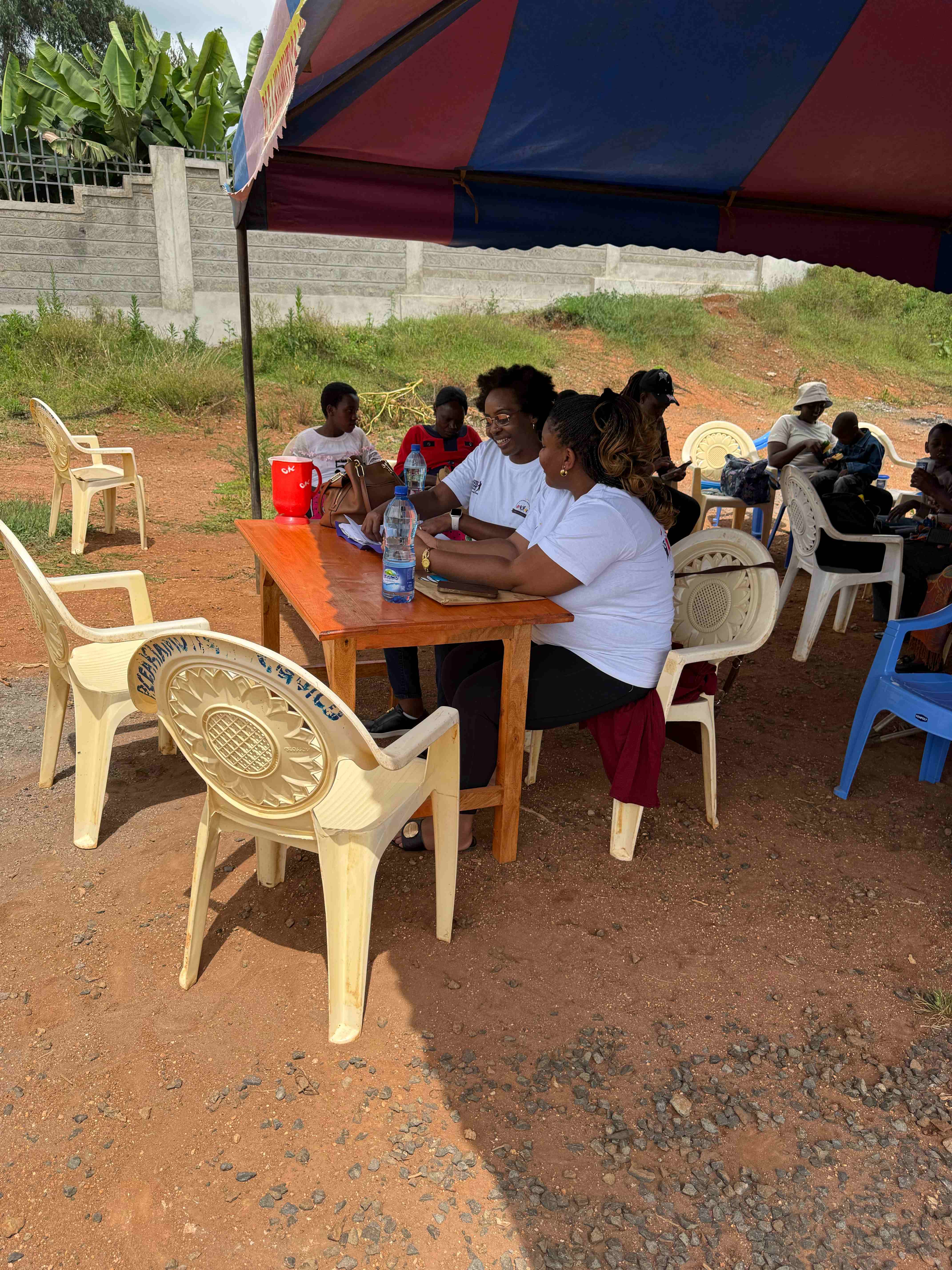 Githima team members at registration table discussing with community members under colorful tent