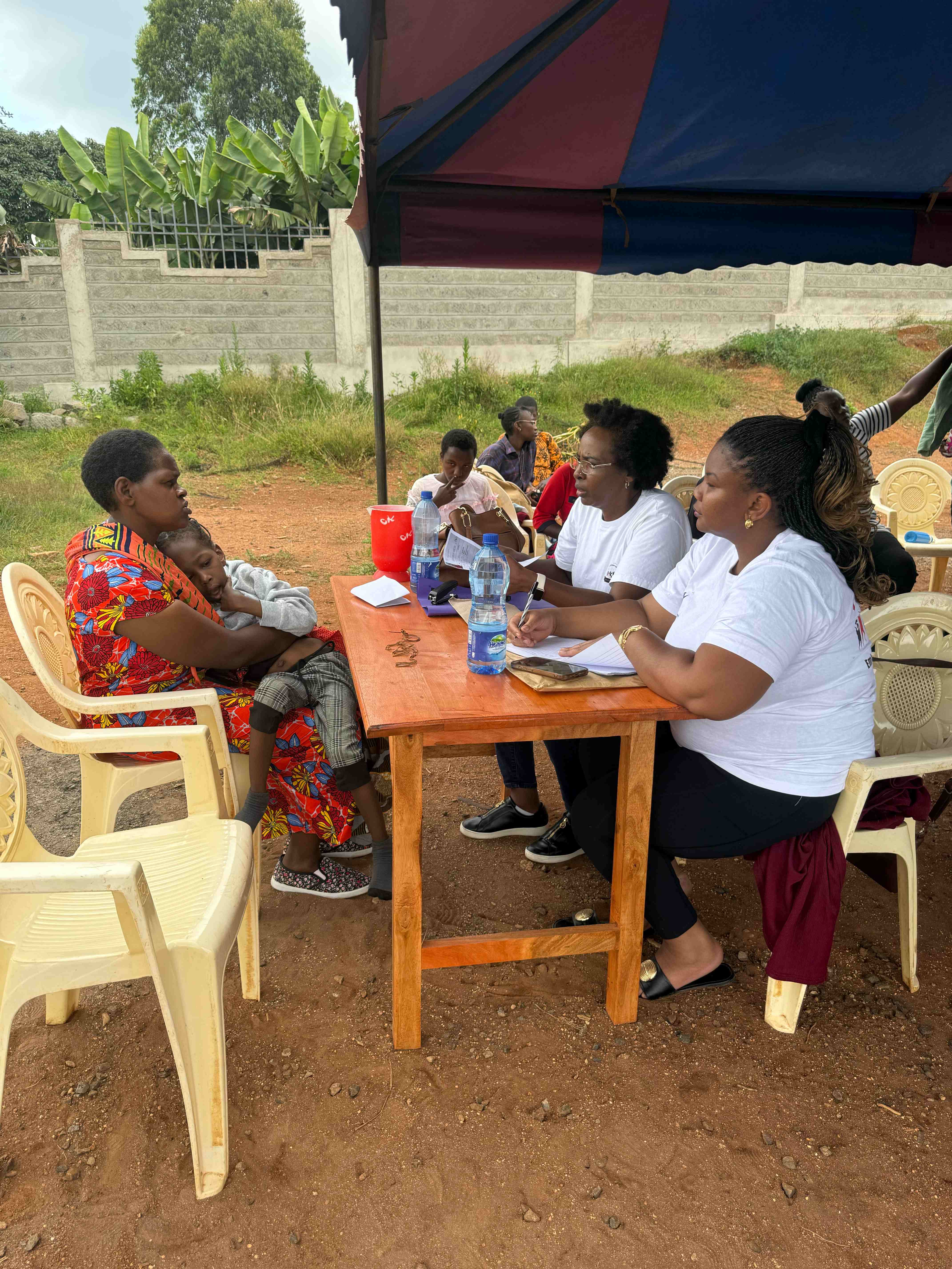 Mother holding child meeting with Githima team members taking notes at community registration