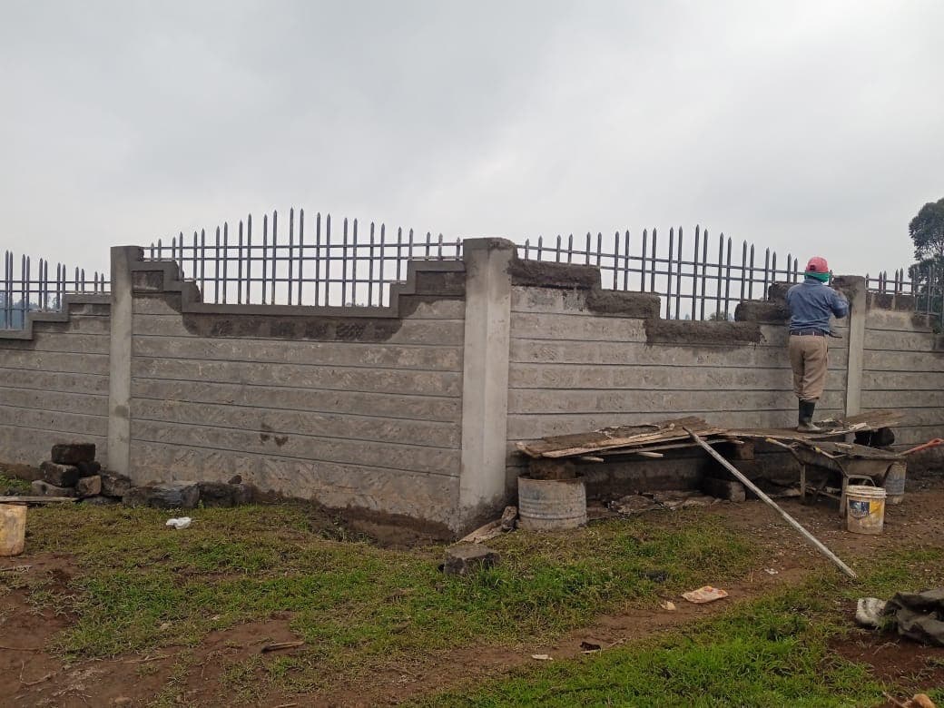 Worker standing on scaffold working on corner section with decorative stepped top and metal railings