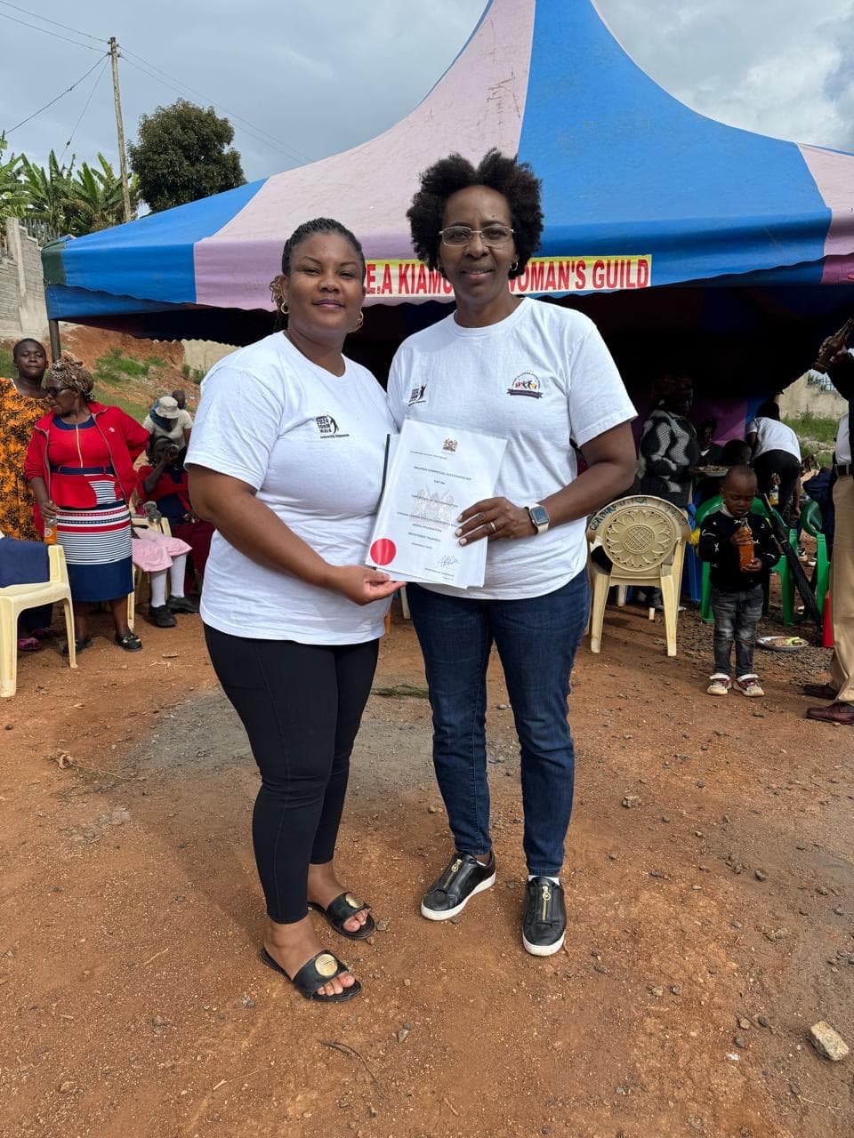 Two women presenting certificate at Githima family celebration