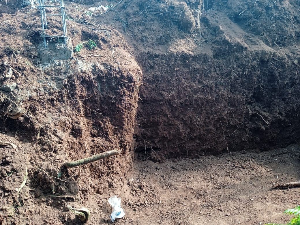 Large excavation site showing exposed red soil