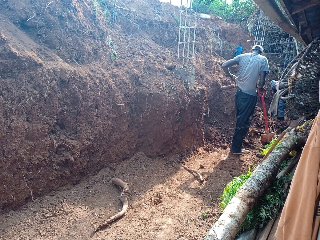 Worker excavating foundation trench with hand tools