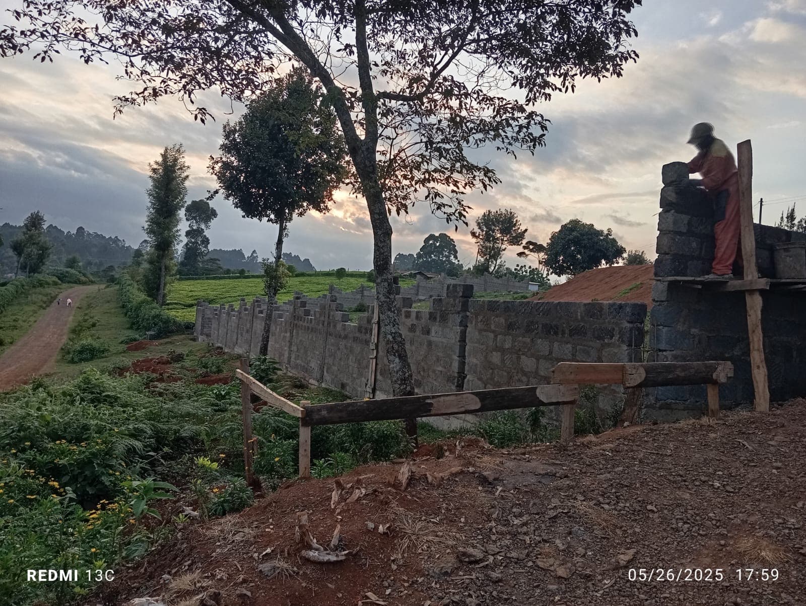 Beautiful sunset view of worker placing blocks on wall pillar with long wall stretching into distance